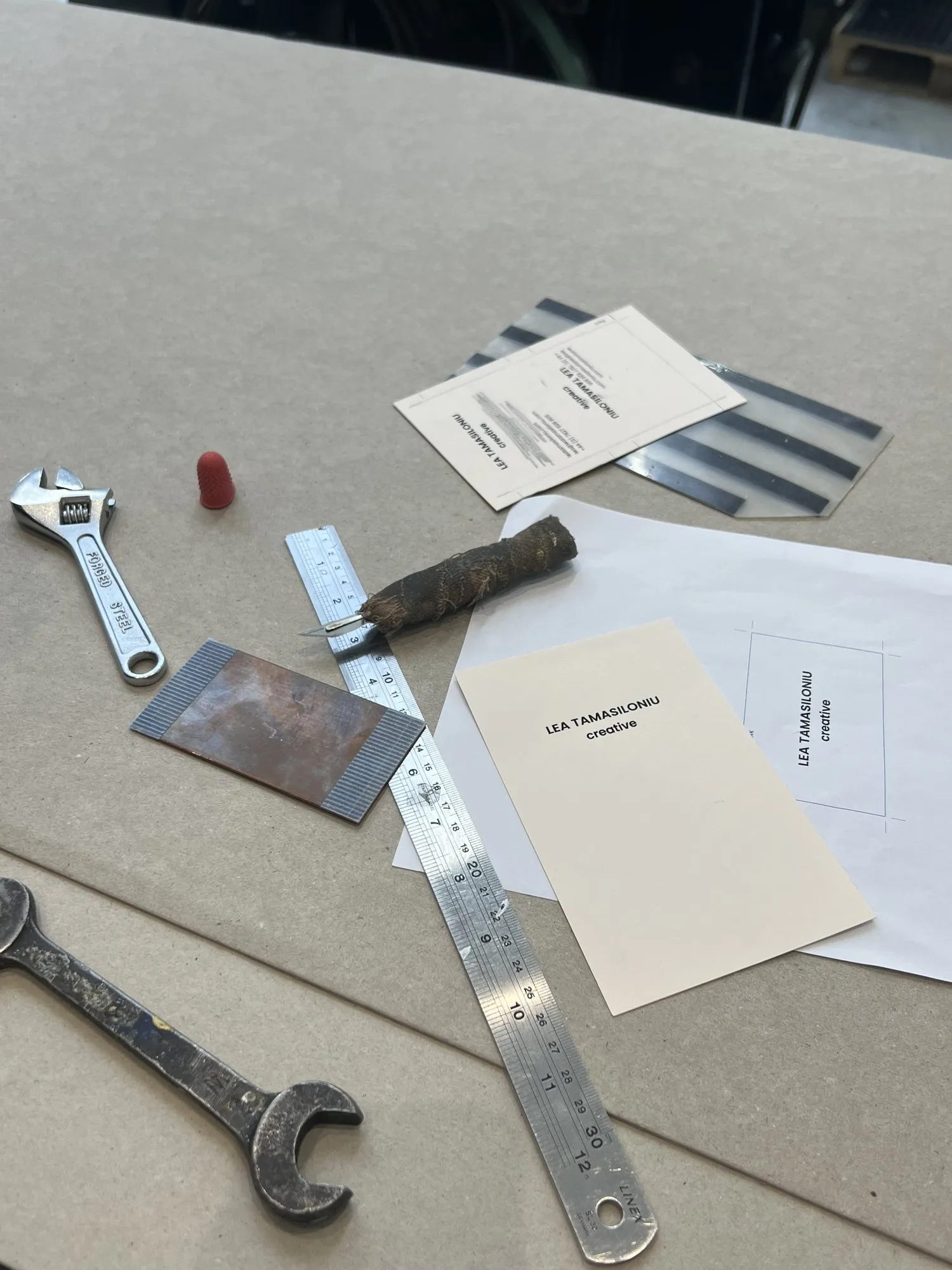 A business card on the workbench with the copper plate and press tools
