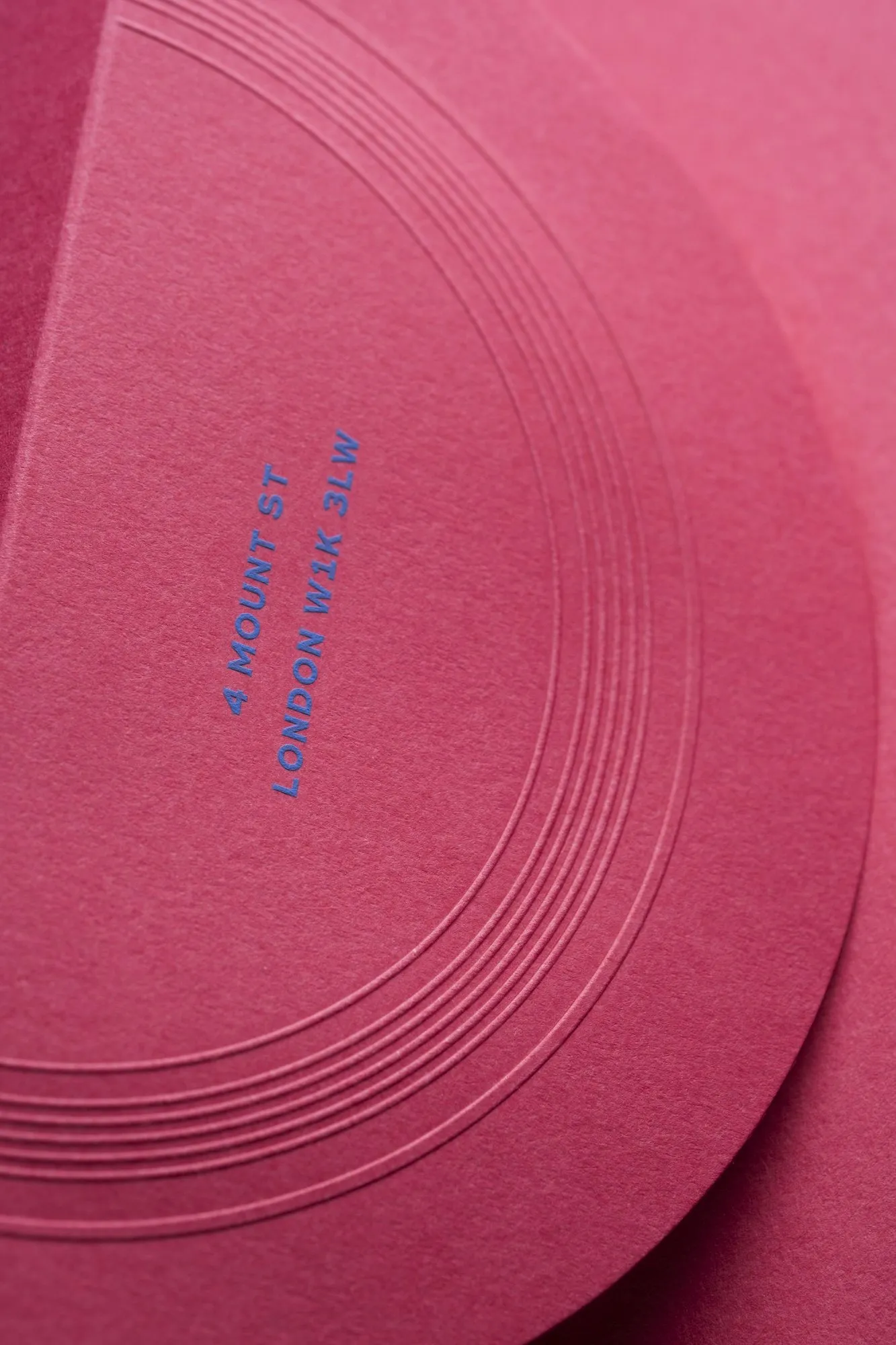 Pink envelope with blue die-stamped address and blind-embossed rings